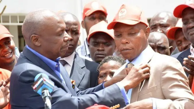 CAPTION: KANU chairman Gideon Moi and Laikipia Senator aspirant Maina Njenga hold the Kanu flag during a press conference at the party's headquarters after the latter's defection from Jubilee, March 22, 2017