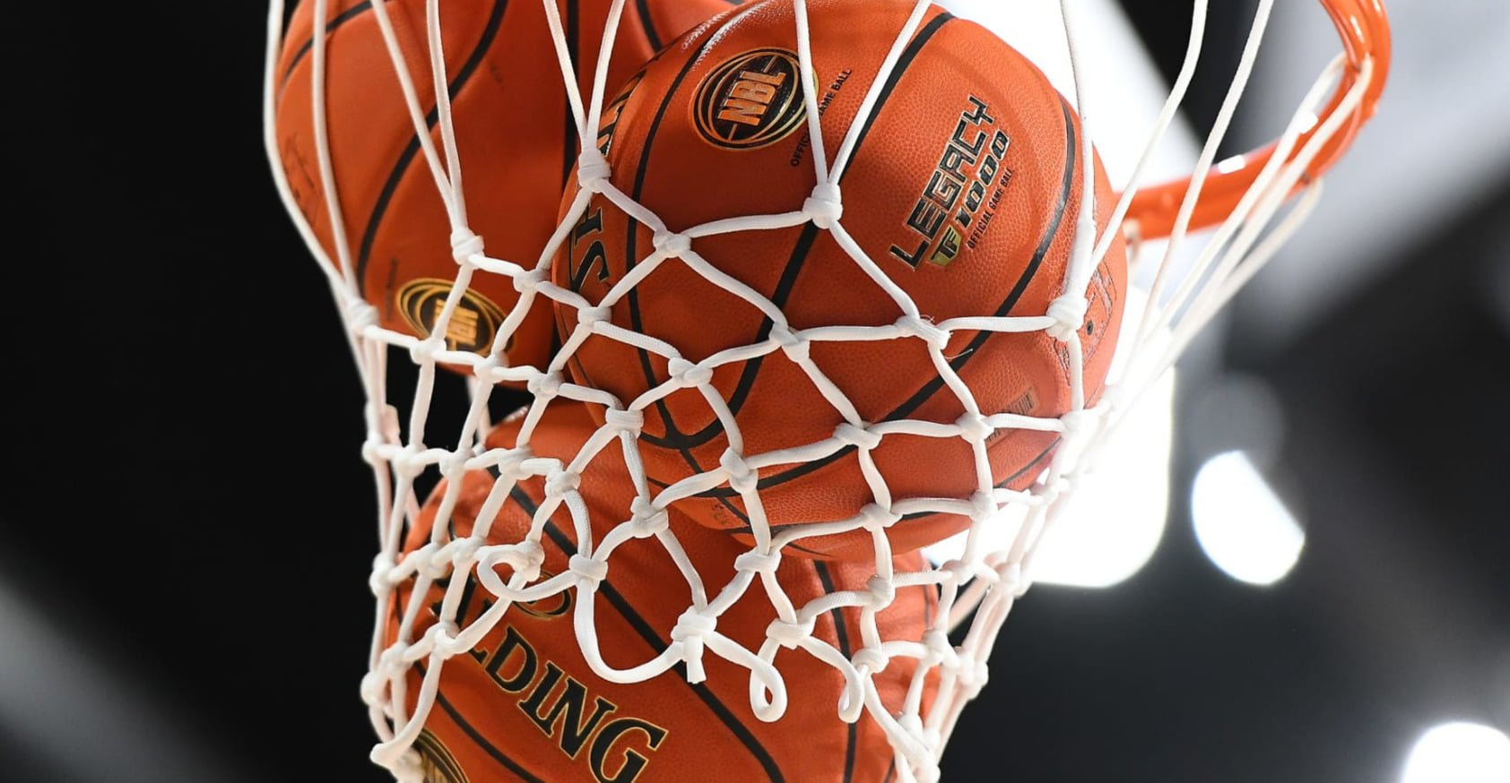 An Image showing a basketball net with three balls hanging within the net