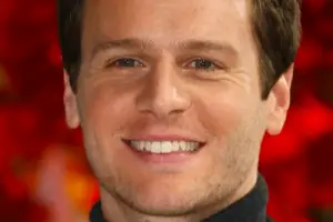 An image of Jonathan Groff smiling confidently in a suit.